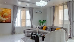 A modern living room with a sofa, coffee table, and a painting on the wall. - MIO Courts (Lekki)