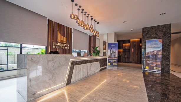 Un hall d’hôtel moderne avec un comptoir en marbre, un mur en bois avec des lambris verticaux et un luminaire suspendu.