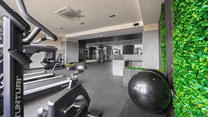 Une salle de sport équipée de matériel d’exercice, un mur recouvert de verdure et un espace d’accueil.