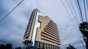 Un hôtel à plusieurs étages au design moderne, doté d’une façade en verre et d’un mélange de balcons et de fenêtres.