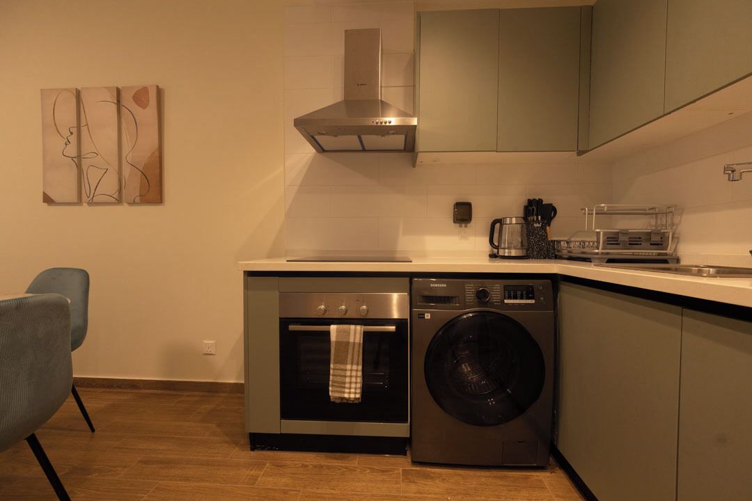A compact kitchen with a built-in oven, a washing machine, and a coffee maker.