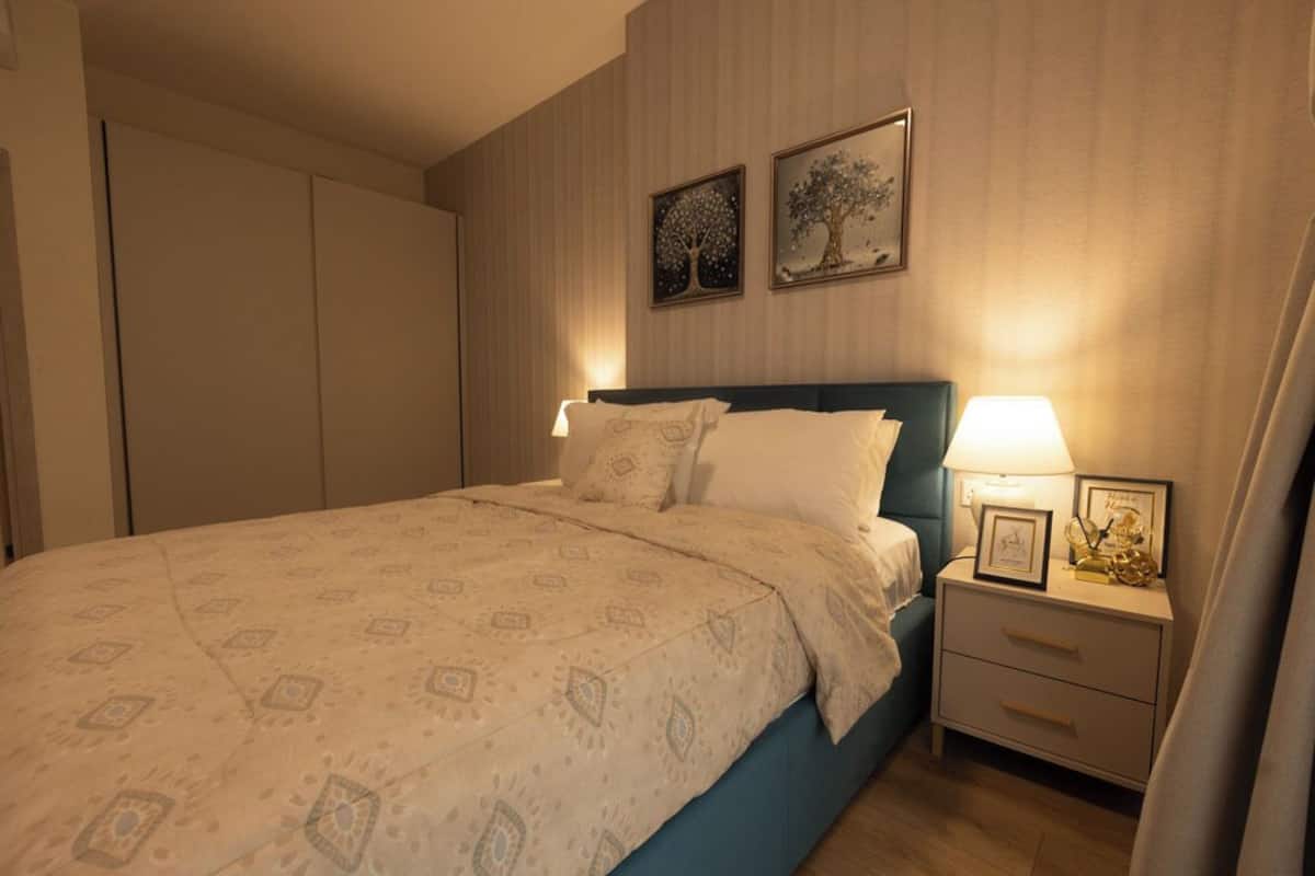 Une chambre à coucher avec un lit, des tables de chevet et deux tableaux encadrés accrochés au mur.