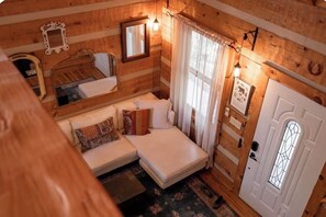Ein gemütliches Blockhaus-Interieur mit Bett, Sofa und einer Tür mit Fenster.