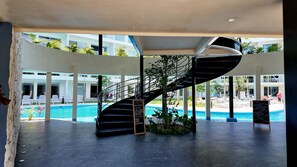 Ein modernes Hotelinnere mit einer Wendeltreppe, einem Pool und einem Schild, das Frühstücksangebote auflistet.