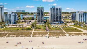 Un hotel sulla costa con diversi edifici alti, una spiaggia sabbiosa e un cielo azzurro limpido.