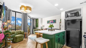 Una cucina moderna con un'isola verde, un frigorifero nero e un'ampia finestra con vista sulla città.