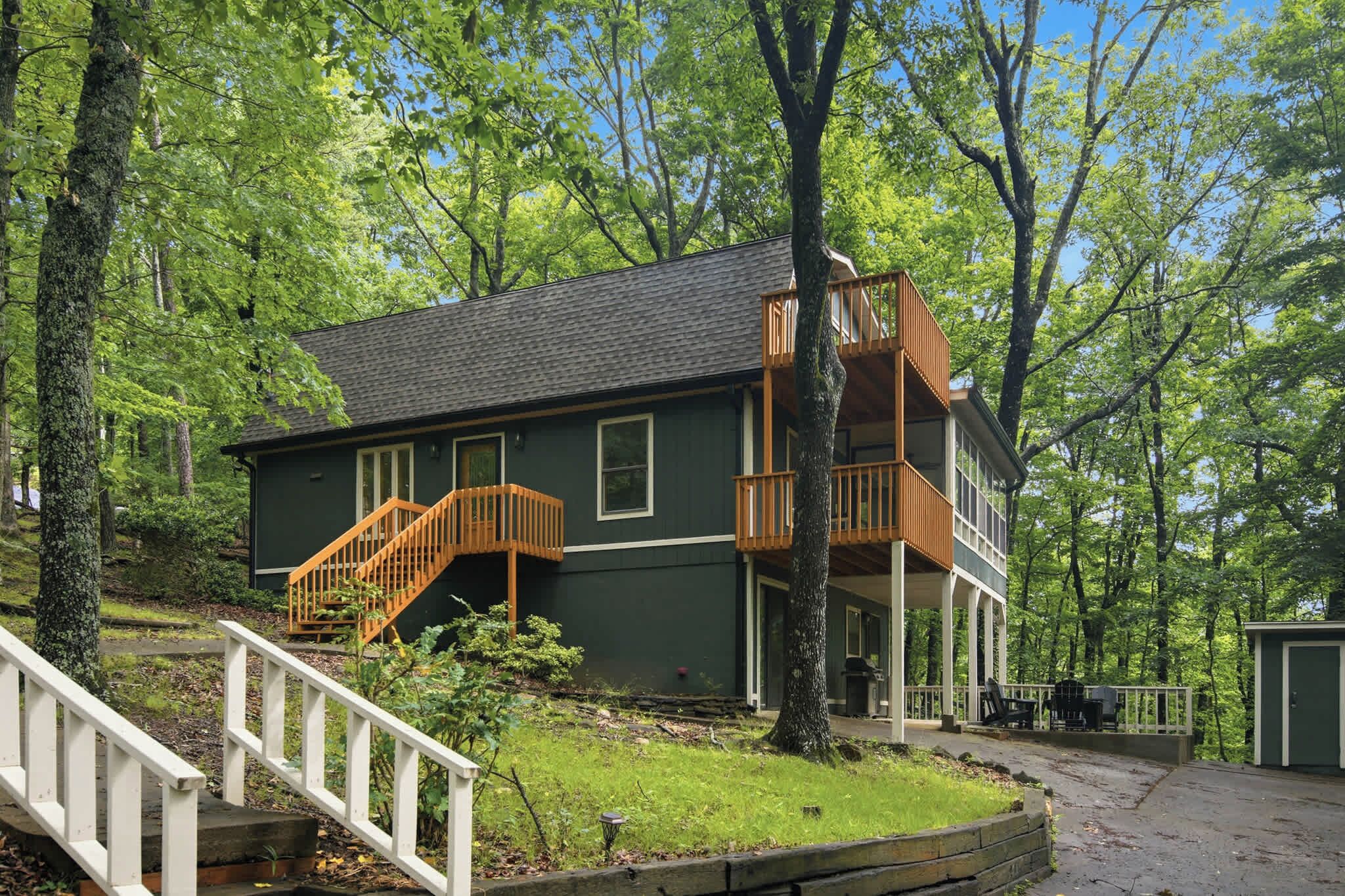 A two-story house with a balcony, surrounded by trees.