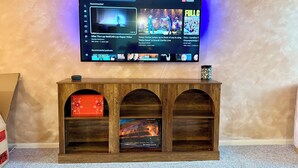 A television mounted on a wall with a wooden entertainment center below.