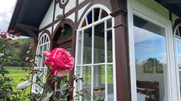 A traditional building with a large window and a rose in the foreground.