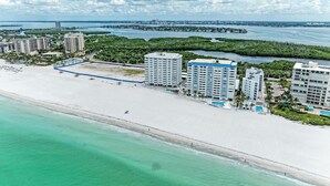 Ein Küstenhotel mit mehreren Hochhäusern, einem Strand und einem Yachthafen.
