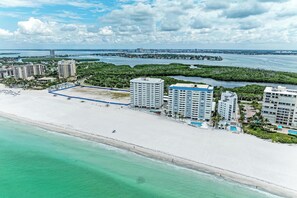 Ein Küstenhotel mit mehreren Hochhäusern, einem Strand und einem Yachthafen.