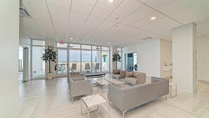 Eine großzügige Lobby mit modernem Design, ausgestattet mit einer Sitzecke, Sofas, Sesseln, einem Couchtisch und Topfpflanzen.