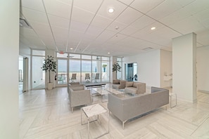 Eine großzügige Lobby mit modernem Design, ausgestattet mit einer Sitzecke, Sofas, Sesseln, einem Couchtisch und Topfpflanzen.
