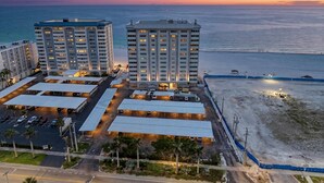 Ein Hochhaus-Hotel mit mehreren Etagen, einem Parkplatz und Blick auf den Strand.