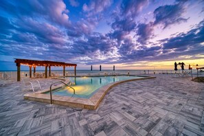 Ein Poolbereich mit Pergola, Liegestühlen und Meerblick.