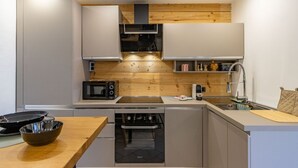 A compact kitchen with wooden accents, a microwave, a sink, and a dishwasher.