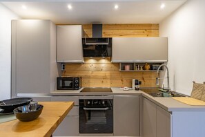 A compact kitchen with wooden accents, a microwave, a sink, and a dishwasher.