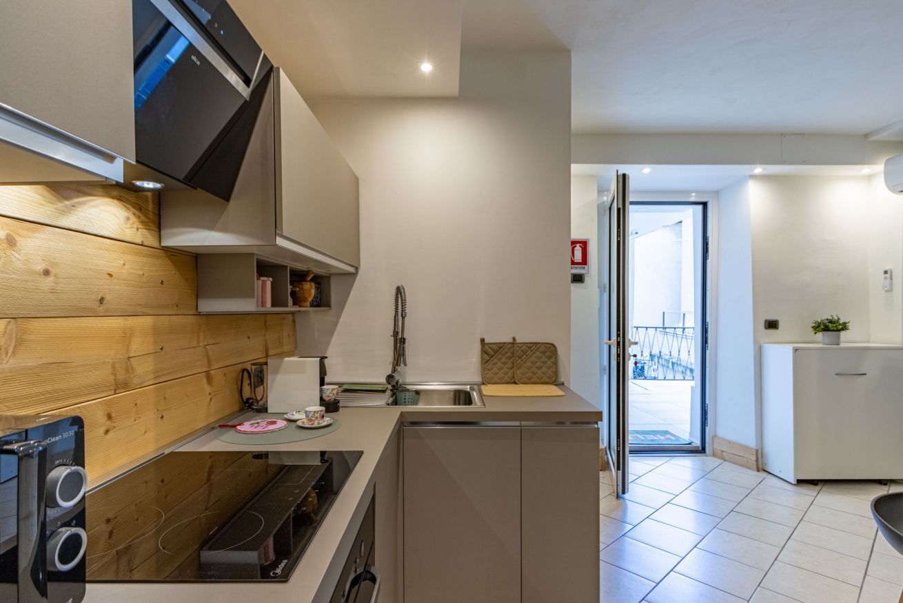 Eine moderne Küche mit eingebautem Ofen, Spüle und einer Holzrückwand.