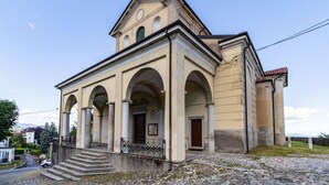 A building with a central entrance, arched columns, and a pitched roof.