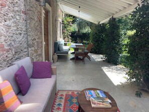 Ein überdachter Außenbereich mit einer Couch, Sesseln und einem Tisch.