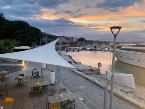 A waterfront restaurant with outdoor seating, a canopy, and a view of boats and water. - Charming House by the Sea in Liguria (Cinque Terre, Porto Venere, Lerici by Boat) (Bocca di Magra)