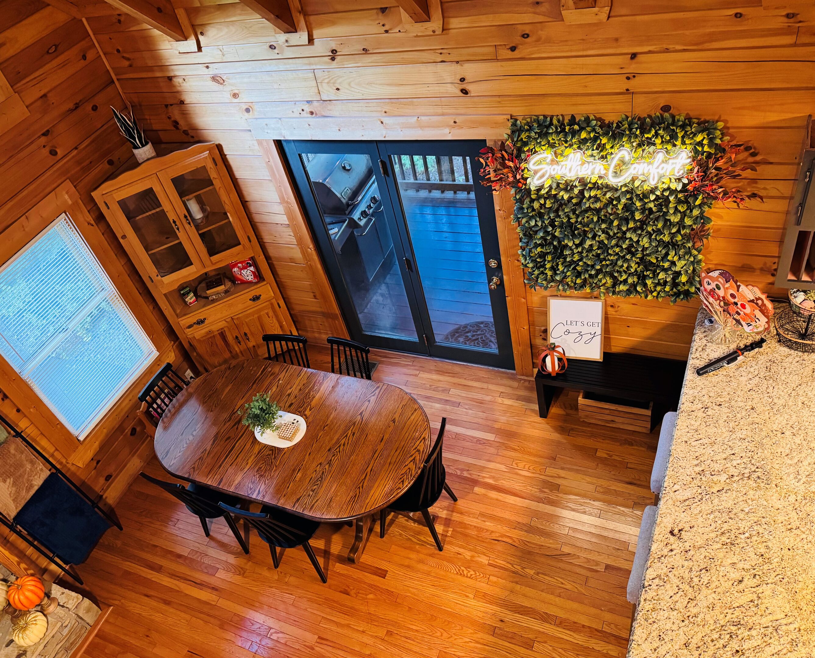 A wooden interior with a dining table, chairs, a grill, and a wall-mounted plant.