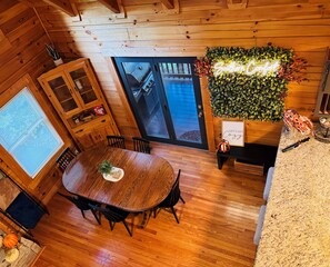A wooden interior with a dining table, chairs, a grill, and a wall-mounted plant. - Cozy 3BR Cabin-Bunk Bed Tent Room-1.5mi to Parkway (Pigeon Forge)