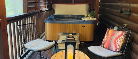 A wooden cabin with a hot tub, a wooden table, and two chairs.