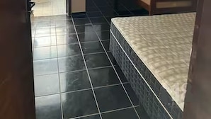 Habitación con literas, piso de baldosas, puerta que da al exterior y aire acondicionado en la pared.