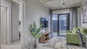 Un salon moderne avec un téléviseur, un canapé vert et une plante en pot.