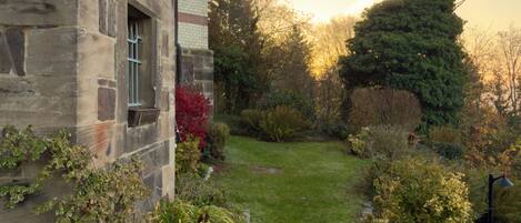 A stone building with a garden path leading to a lawn.