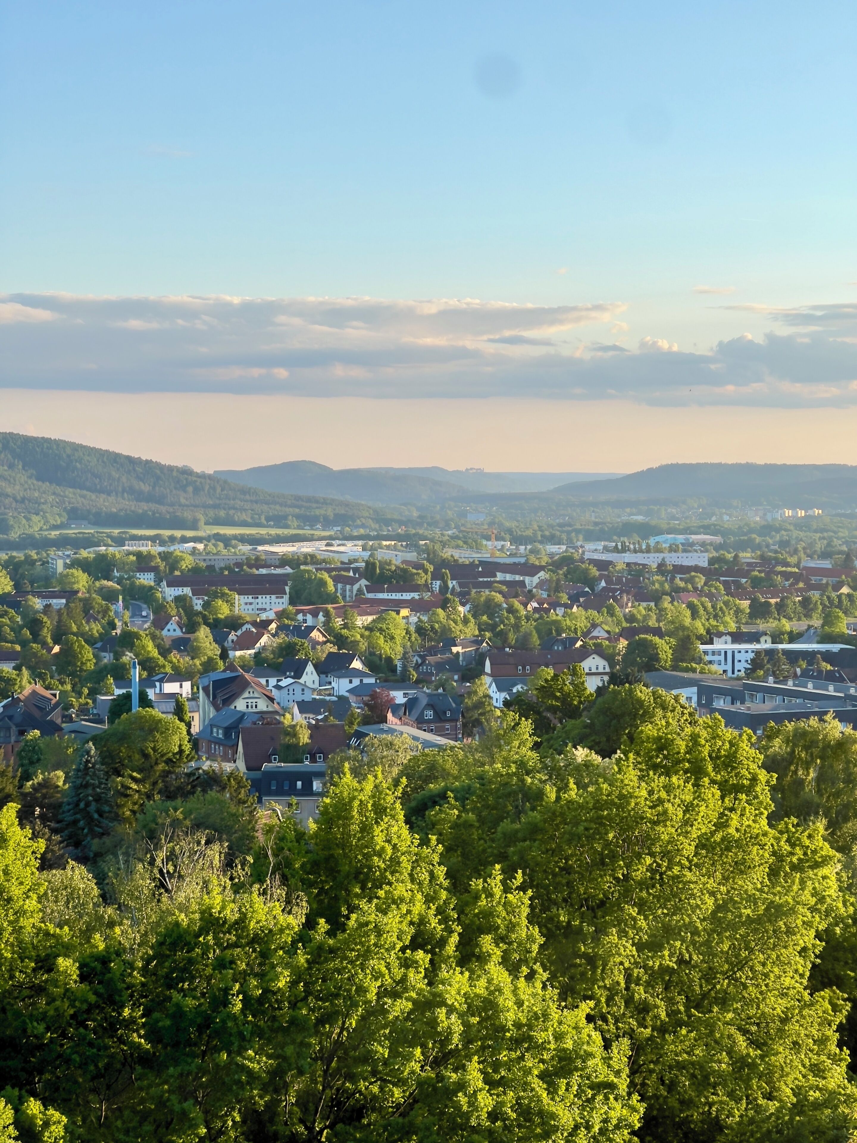 Eine Stadt mit Wohngebäuden, einem markanten Kirchturm und umgebender Grünfläche.