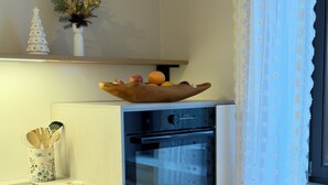 Keittiössä on sisäänrakennettu uuni, puinen kulho työtasolla ja pieni joulukuusi.