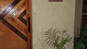 Una puerta de madera con un motivo de chevron, una planta en maceta y un cartel en la pared.