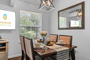 A dining area with a table set for four, a vase with flowers, and a large mirror on the wall. - Eagle's View Condo at Fall Creek (Branson)