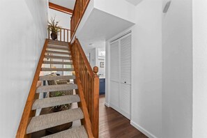 A staircase with wooden railings and carpeted steps leading to a room with a white door and a plant. - Eagle's View Condo at Fall Creek (Branson)