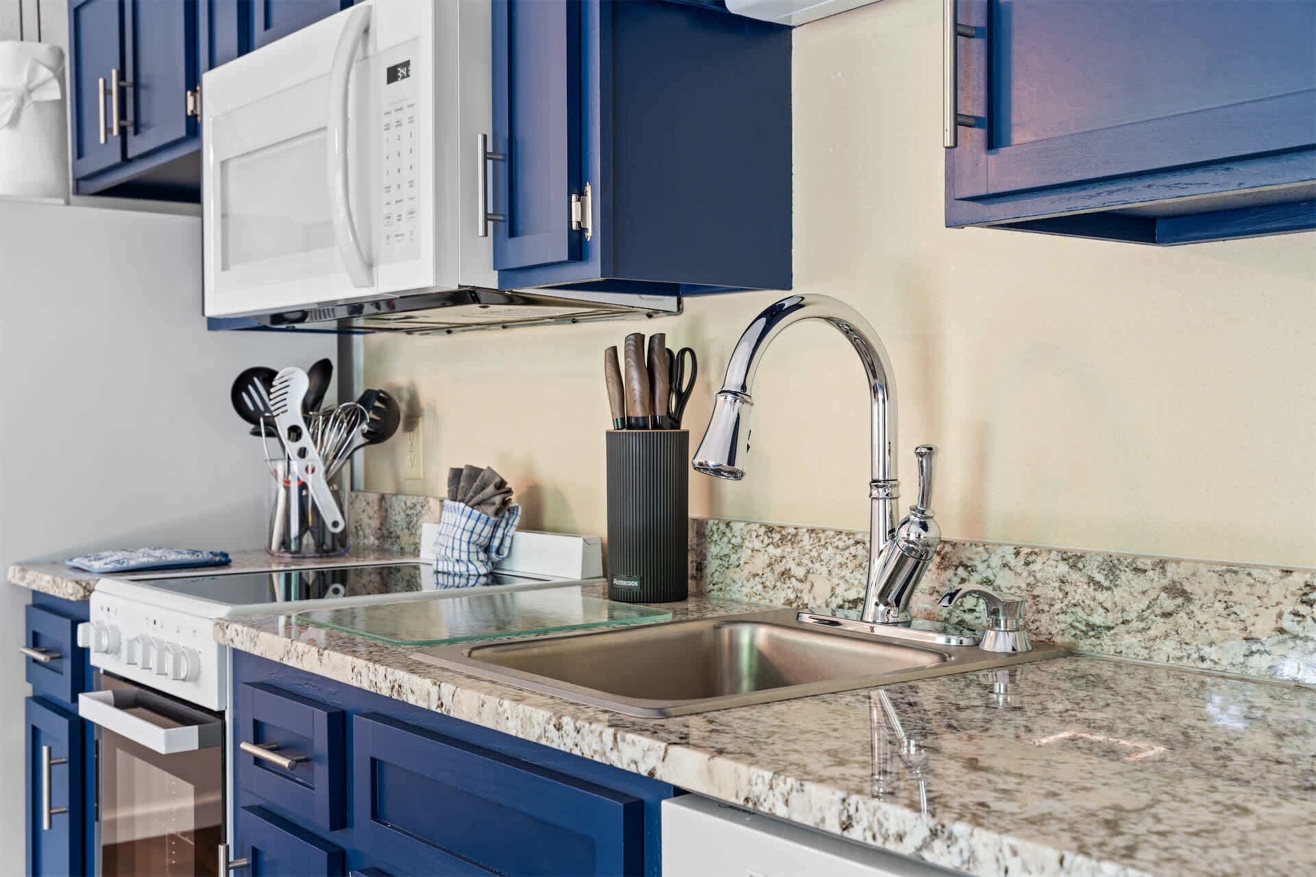 Una cocina con un lavamanos de acero inoxidable, un microondas y una campana extractora.
