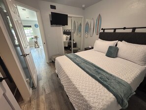 Ein Schlafzimmer mit einem Bett, einem Fernseher und einer Tür zu einem anderen Raum.