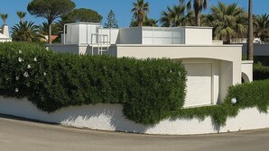 En moderne bygning med hvid facade, garage og en velplejet hæk.