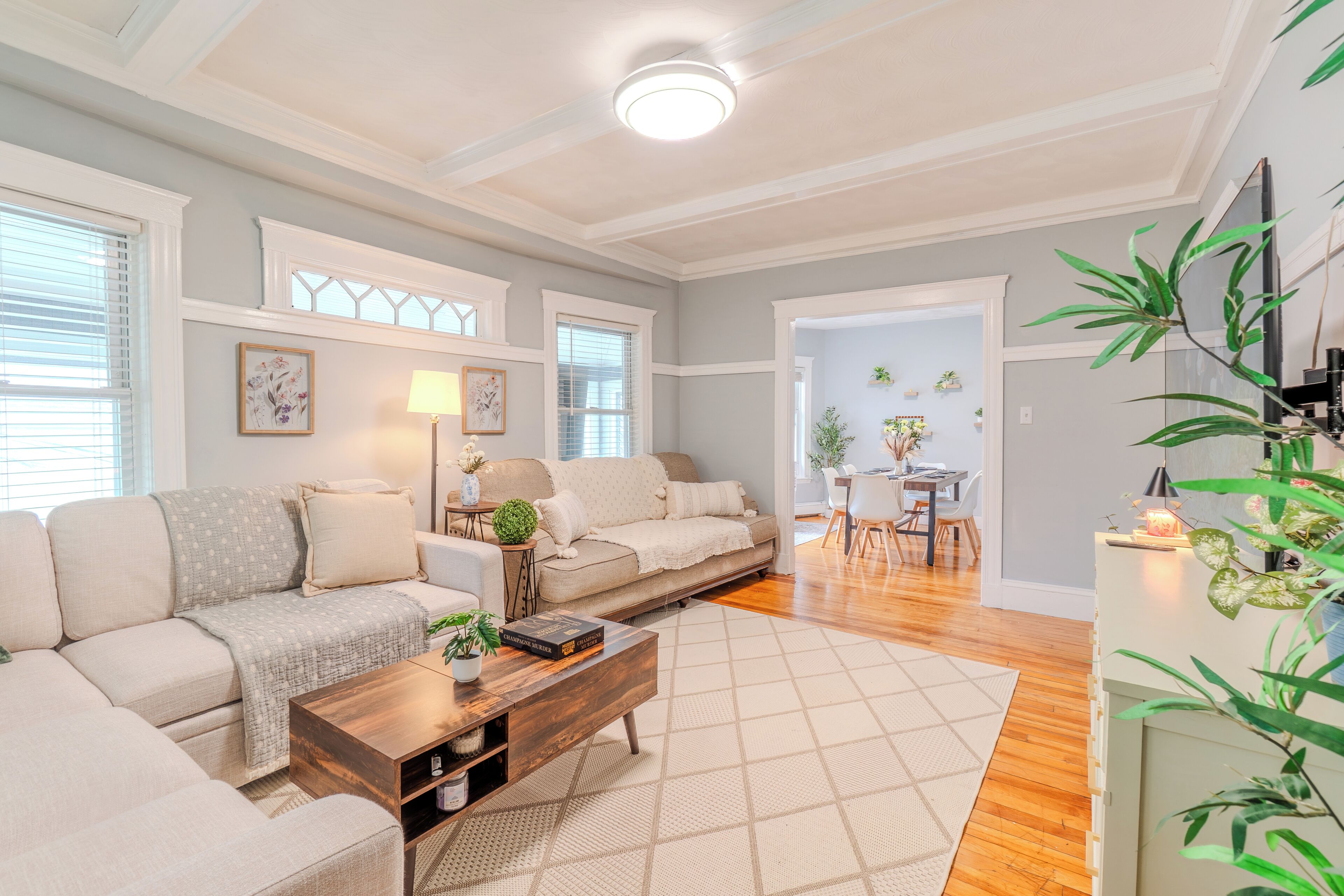 A living room with a sofa, coffee table, and a dining area with chairs and a table.