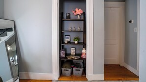 Un couloir étroit doté d’une bibliothèque intégrée, où sont rangés des livres, des objets décoratifs et des boîtes de rangement.