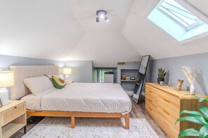 Ein Schlafzimmer mit Bett, Nachttischlampen, einem Schminktisch, einem Spiegel und einem Oberlicht.