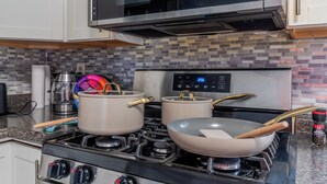 Une cuisine équipée d’un four à micro-ondes, de deux casseroles sur la cuisinière et d’une horloge numérique.