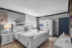 Ein Schlafzimmer mit Bett, Nachttischen, einem Kleiderschrank und einer Tür.