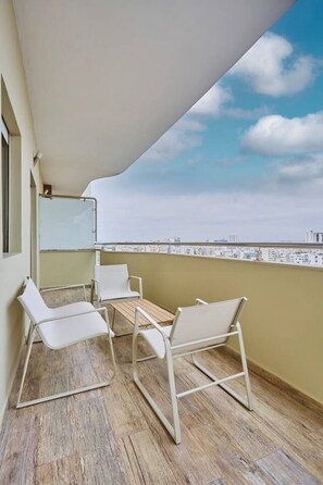 Ein Balkon mit Tisch und Stühlen, ein weißes Markisen und Blick auf die Stadt.