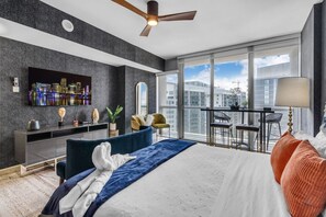 A modern hotel room with a large bed, a balcony with a table and chairs, a TV mounted on the wall, and a city view. - Luxury Studio at Icon Brickell | Skyline Views (Miami)