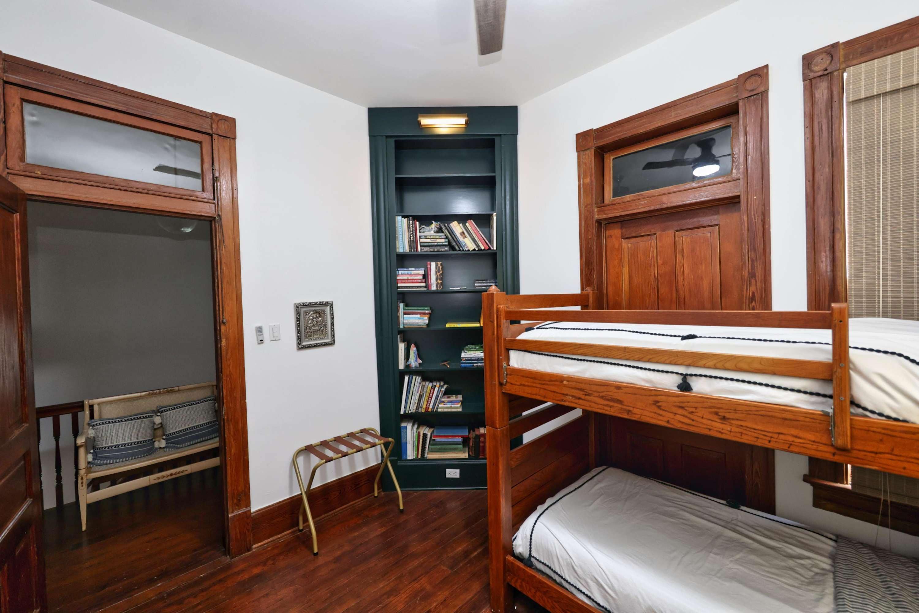 A room with two bunk beds, a wooden bookshelf, and a small ladder.