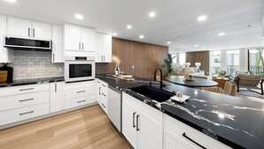 A modern kitchen with white cabinets, a black countertop, and a built-in microwave. - Stunning Views in Bankers Hill! (San Diego)