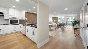 A modern kitchen with white cabinetry, a built-in oven, and a wooden accent wall. - Stunning Views in Bankers Hill! (San Diego)