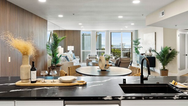 A modern kitchen with a central island, a dining area with a round table, and a view of the outdoors. - Stunning Views in Bankers Hill! (San Diego)
